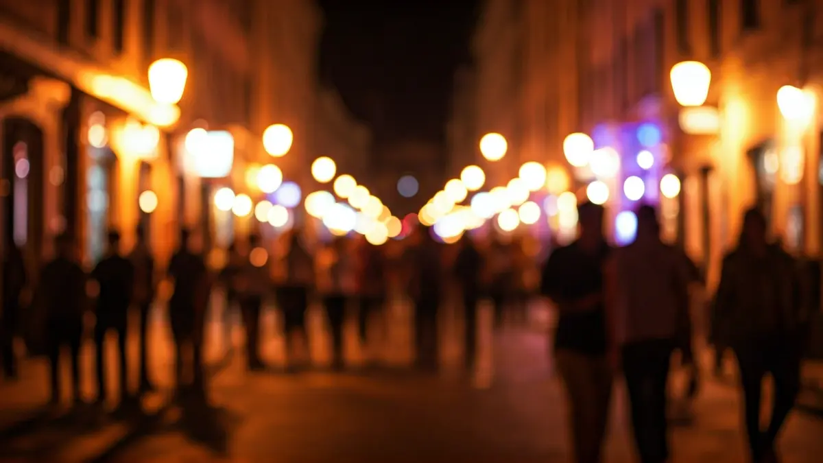 Imaxe xenérica dunha rúa animada de noite, con luces de locais de ocio e siluetas de persoas.