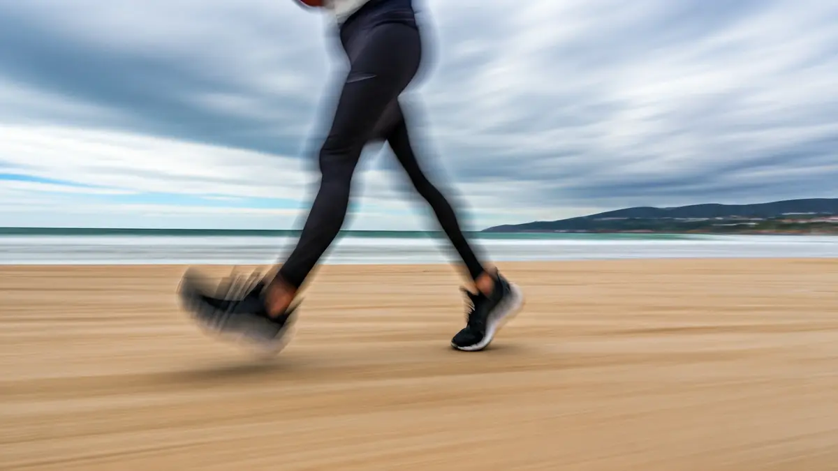 Imaxe dun corredor en plena carreira nunha praia galega.