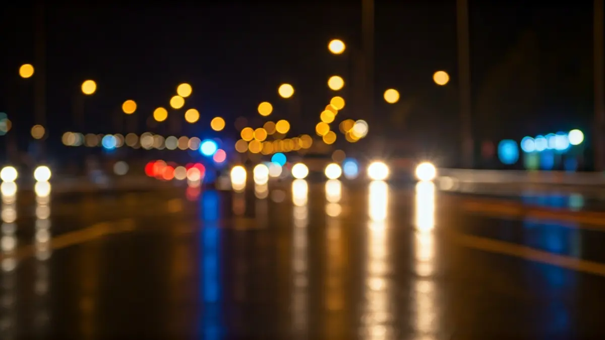 Imagen genérica de luces de emergencia reflejándose sobre asfalto mojado por la noche.