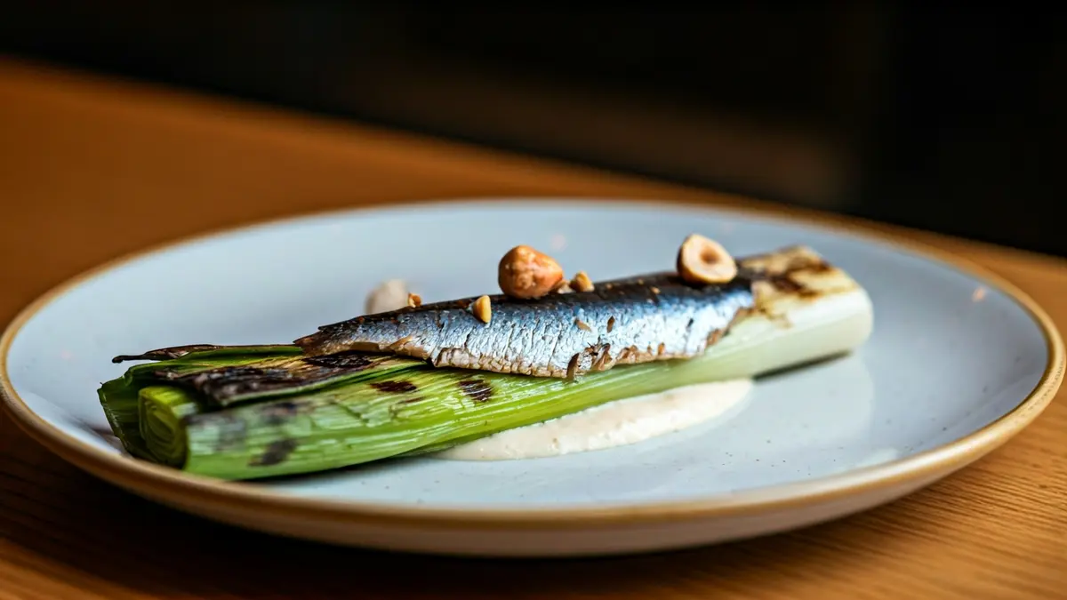 Plato gourmet con puerro a la brasa, salsa holandesa de koji y majada de sardina ahumada y avellana.
