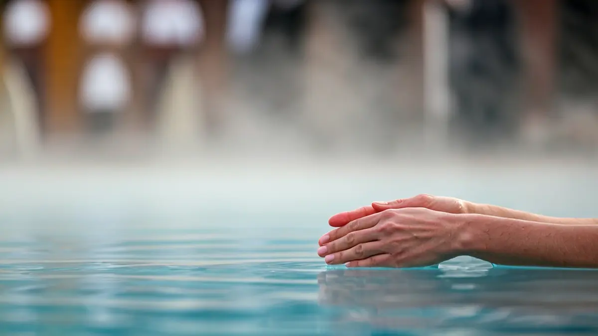 Imaxe xenérica de auga termal nun balneario, con mans tocando a superficie.