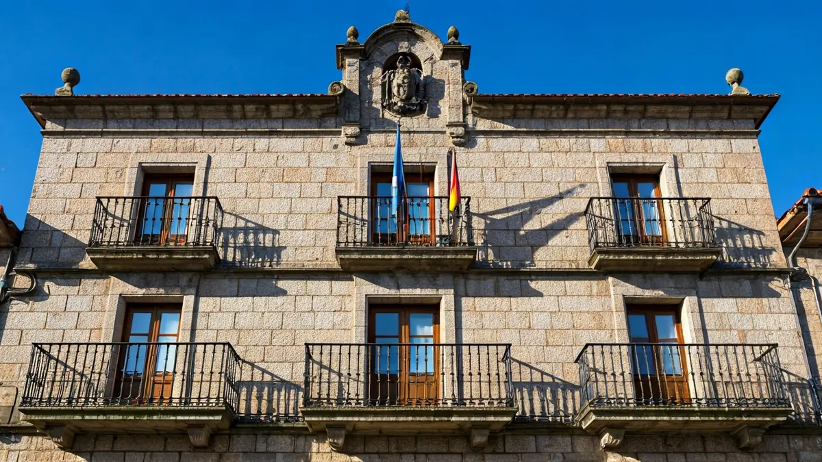 Fachada de un ayuntamiento gallego con balcón y luz solar.