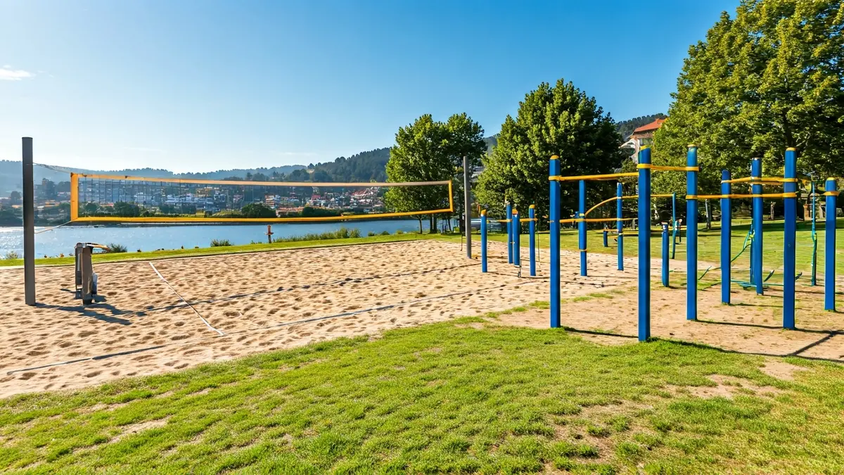 Imaxe dun circuíto de calistenia e unha pista de voleibol ao aire libre xunto a un río.