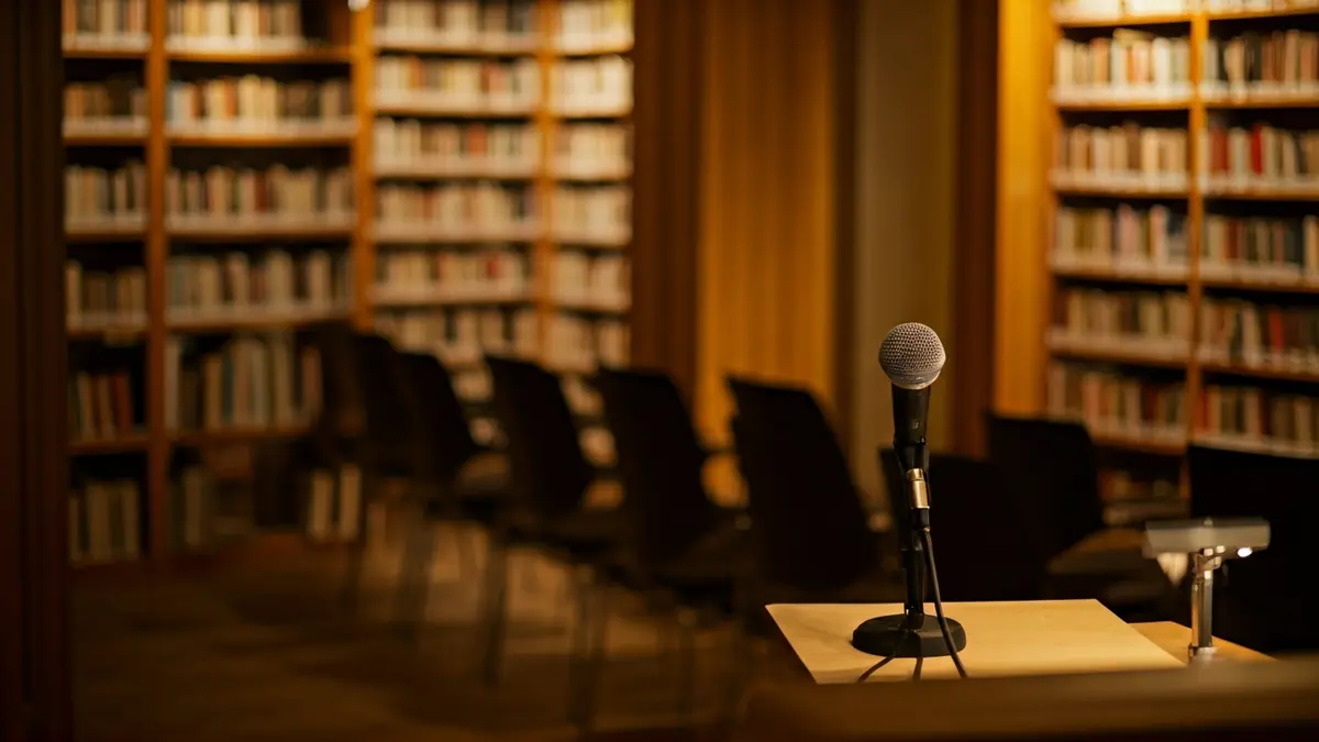 Imagen genérica de una sala de proyección o biblioteca con sillas vacías y un micrófono.