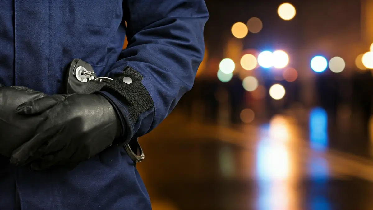 Imaxe xenérica de mans dun axente de policía con esposas.