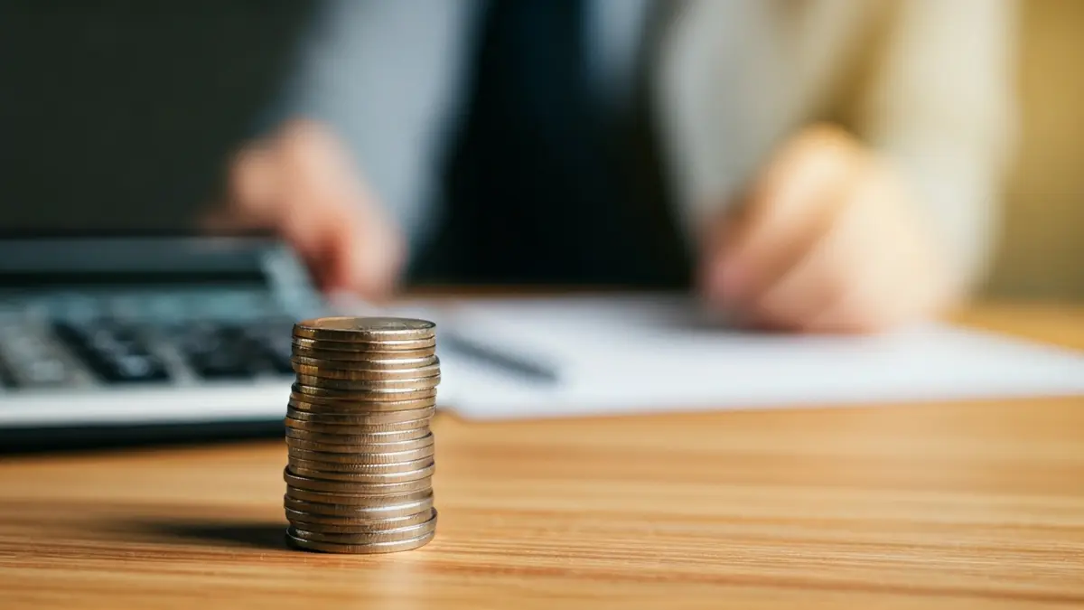 Imaxe xenérica de moedas e billetes de euro sobre unha mesa, simbolizando débeda e problemas financeiros.