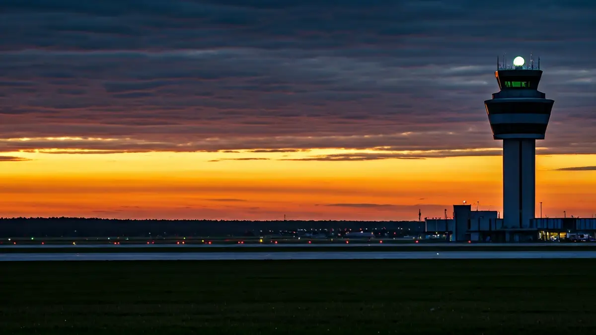 Torre de control dun aeroporto ao anoitecer, con luces de aeronaves borrosas na pista, simbolizando a folga de controladores.