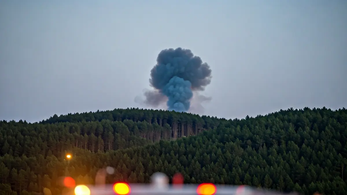 Imagen genérica de una columna de humo sobre un monte gallego, con luces de emergencia borrosas.