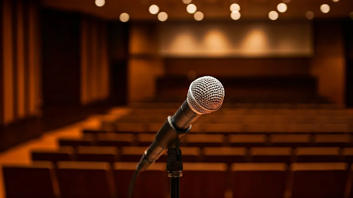 Imaxe xenérica dun auditorio baleiro cun micrófono no atril, preparado para unha conferencia.