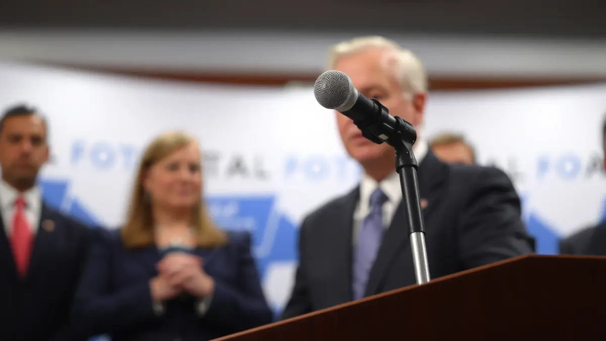 Imaxe xenérica dun atril con micrófono nunha rolda de prensa.