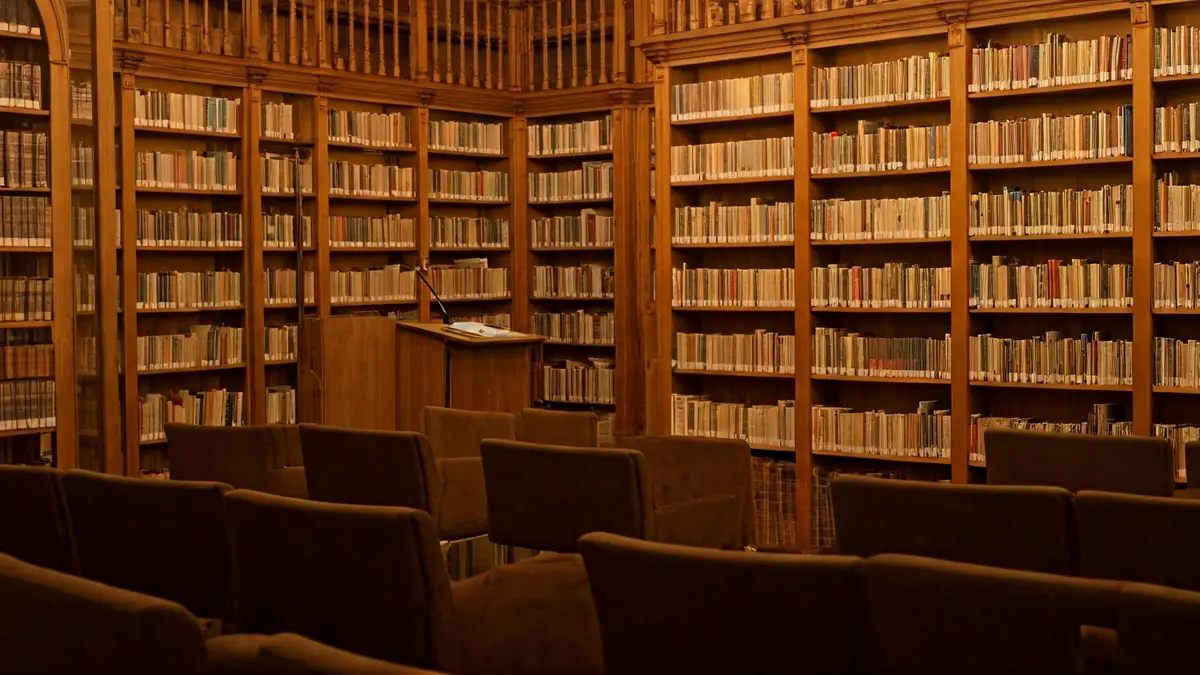 Imaxe xenérica dunha biblioteca ou sala de actos, con estantes de madeira e un micrófono nun podio.