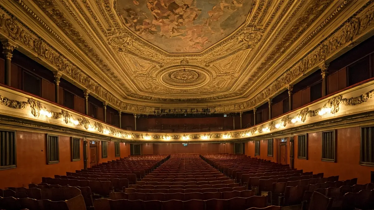 Imaxe do interior dun teatro histórico con danos no teito e andamios.