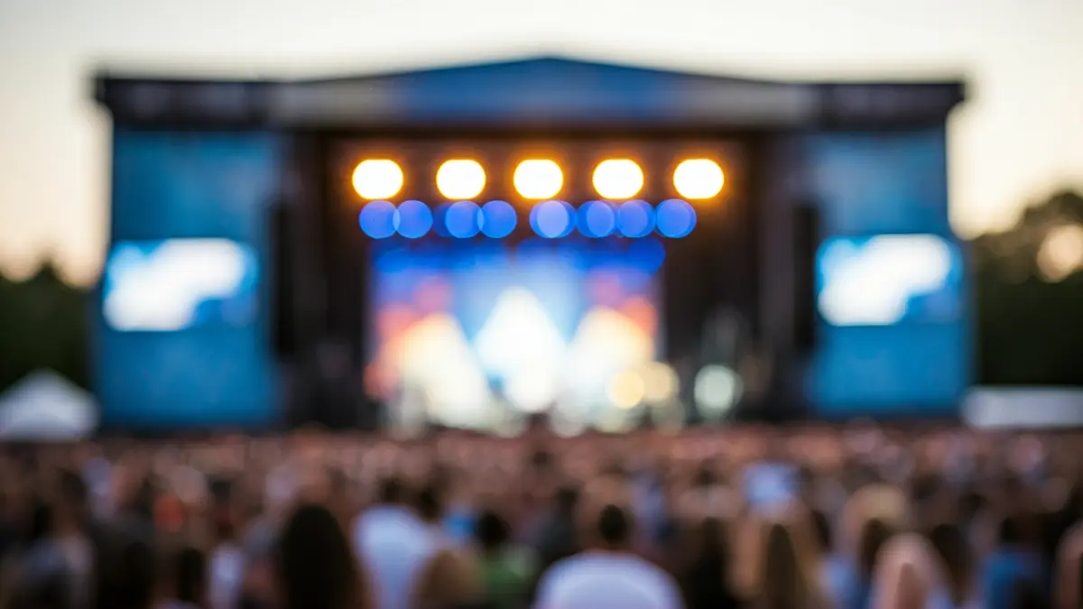 Imaxe xenérica dun escenario de festival de música ao anoitecer, con luces e unha multitude borrosa.