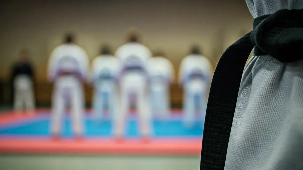 Imaxe xenérica dun cinto de taekwondo, con fondo borroso dun dojo.