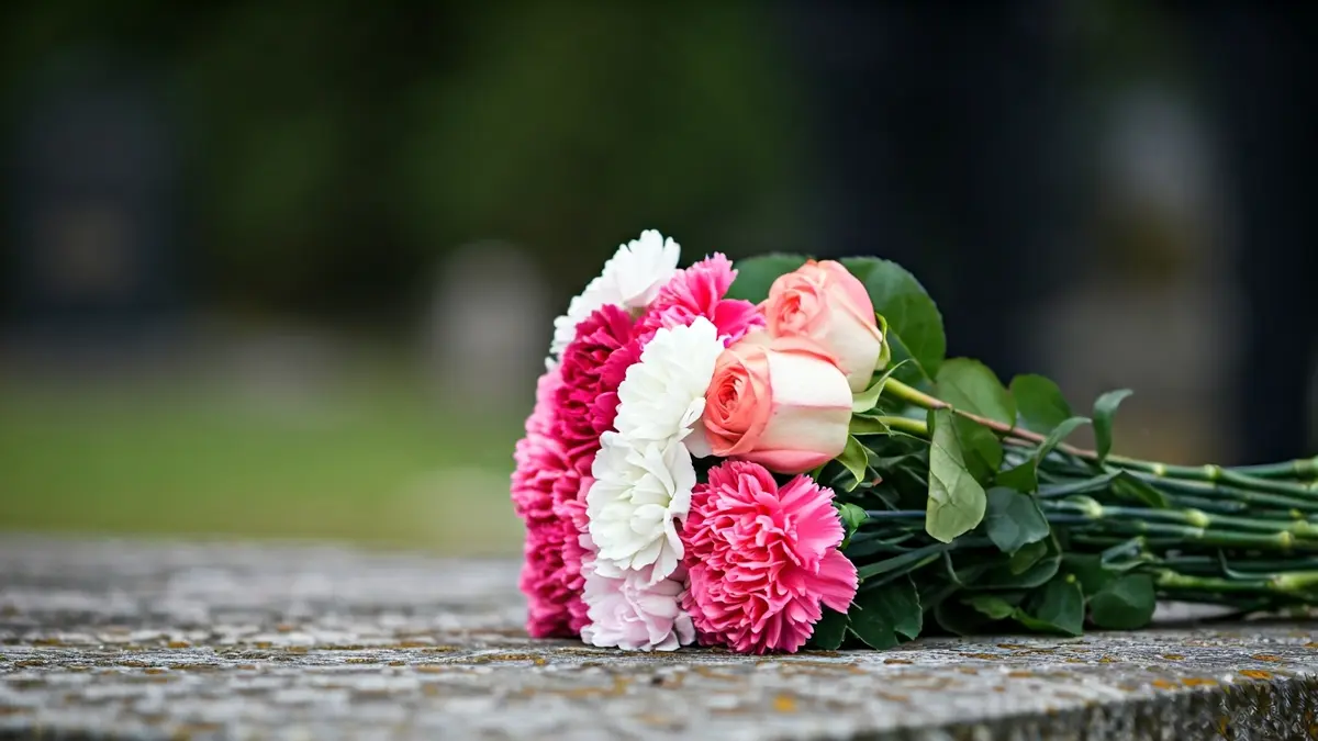Imaxe xenérica dun ramo de flores depositado nunha superficie de pedra, simbolizando unha homenaxe.