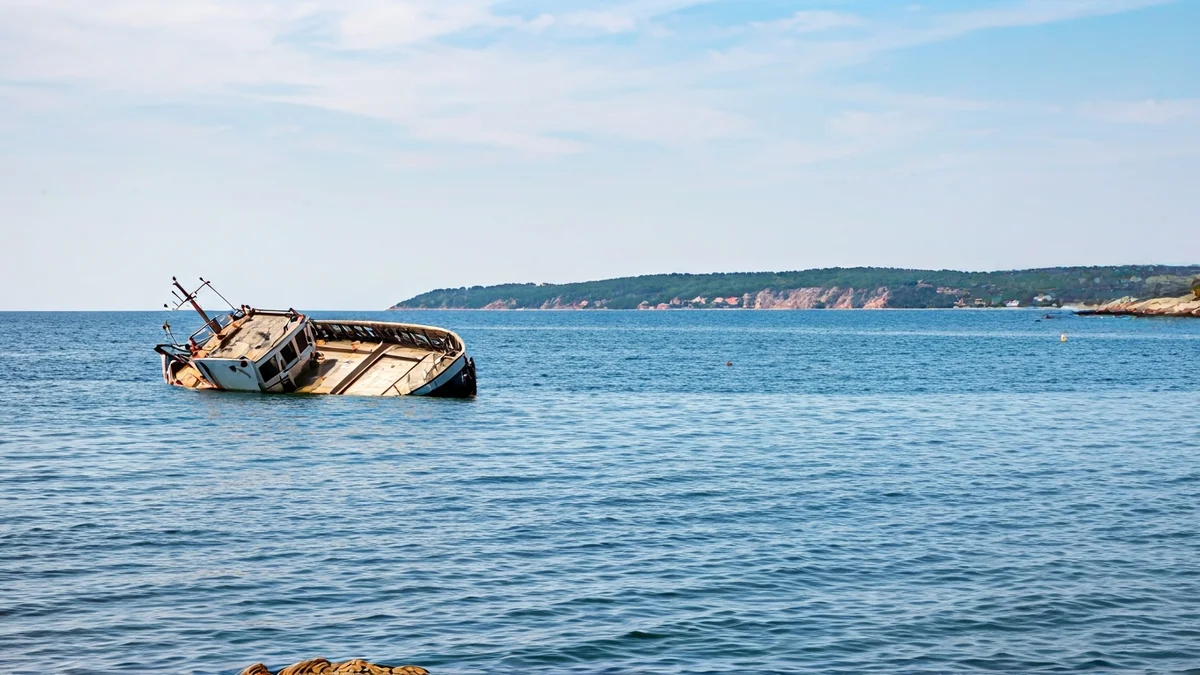 Imaxe dunha planeadora envorcada preto da costa.