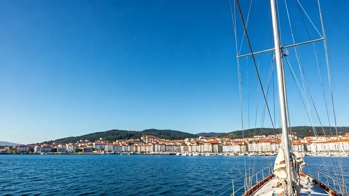 Imagen de un mástil de velero en Sanxenxo, con la costa de fondo.