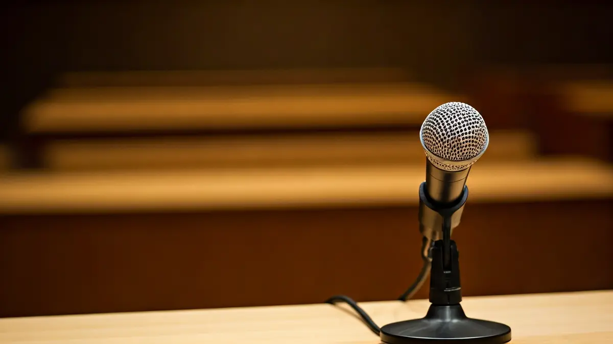 Imaxe xenérica dun micrófono nun atril nunha sala de conferencias, simbolizando un evento literario.