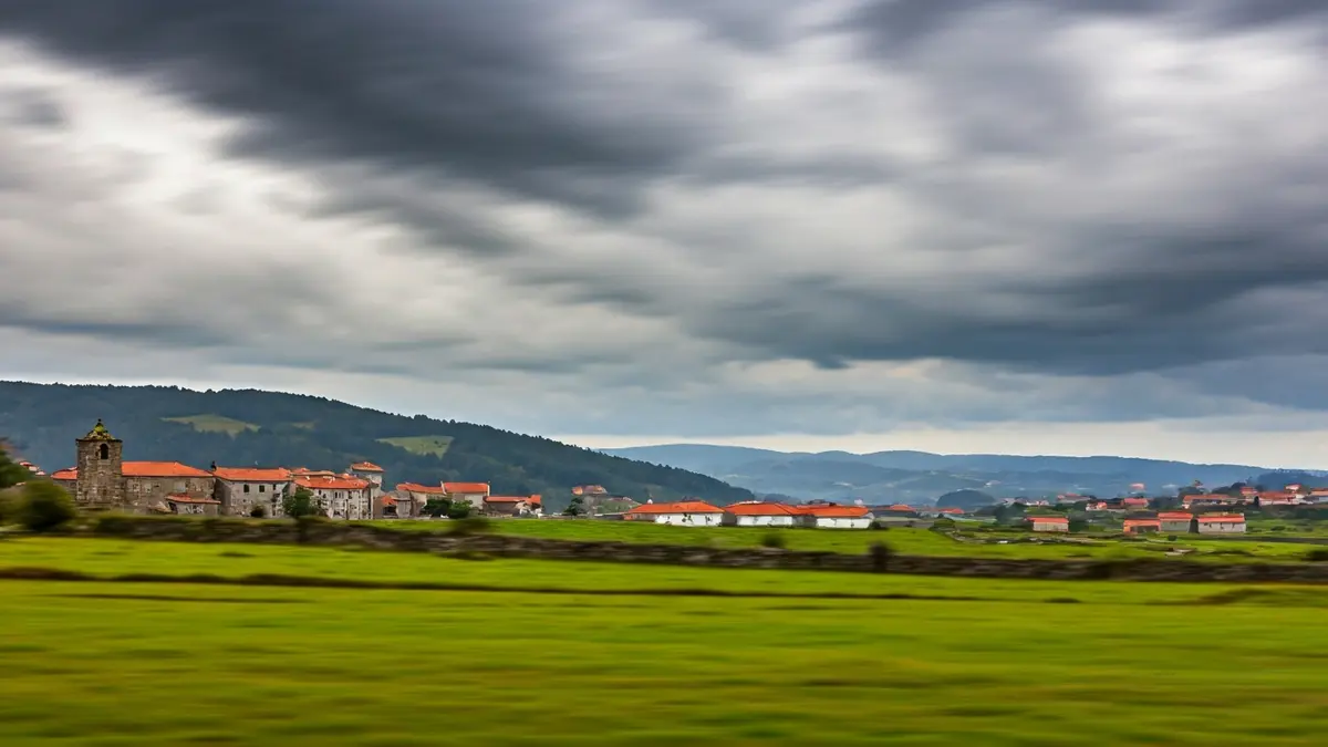 Imaxe xenérica dun ceo anubrado e chuvioso sobre unha paisaxe rural galega.