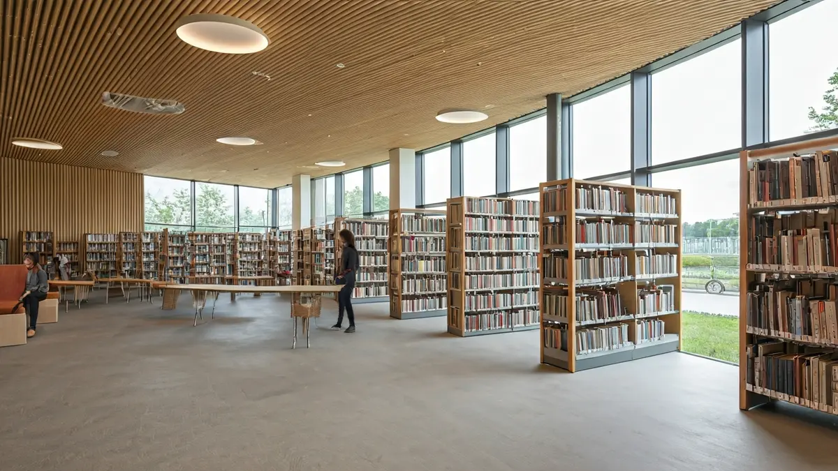 Imagen de una biblioteca moderna y sostenible con grandes ventanales y espacios de lectura.