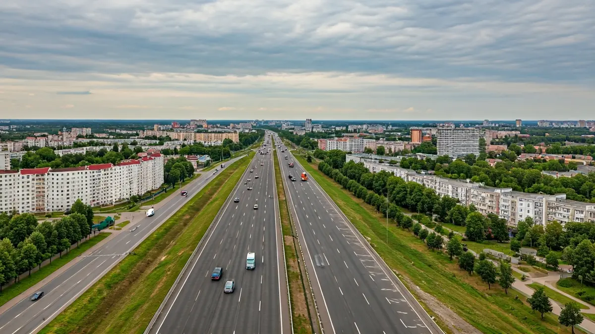 Imaxe aérea dunha autoestrada entrando nunha cidade, con edificios residenciais e zonas verdes.