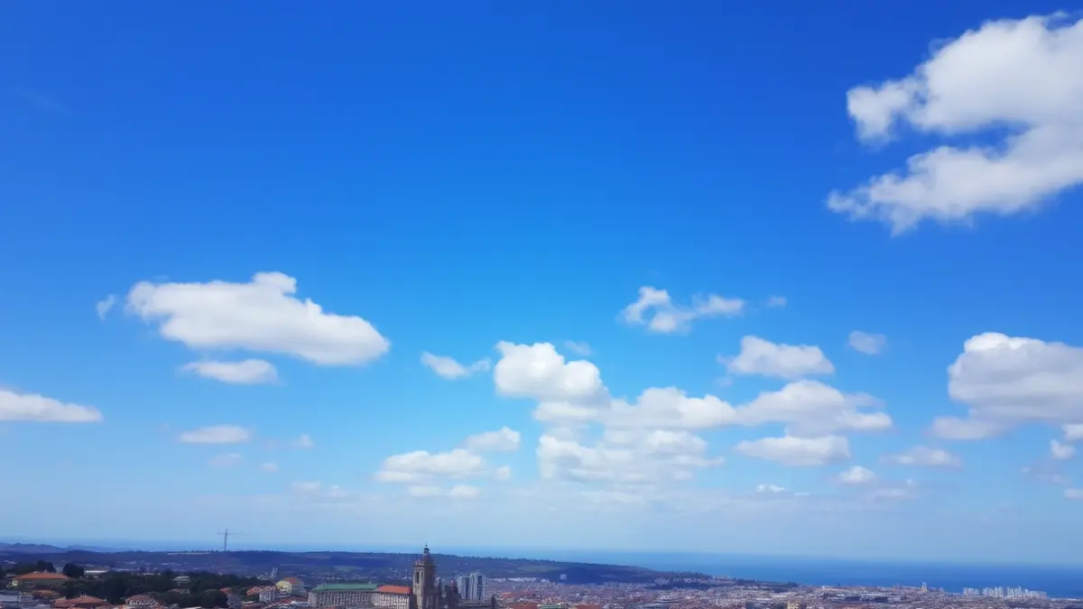 Imaxe xenérica dun ceo con nubes altas sobre unha cidade costeira, representando o tempo primaveral.