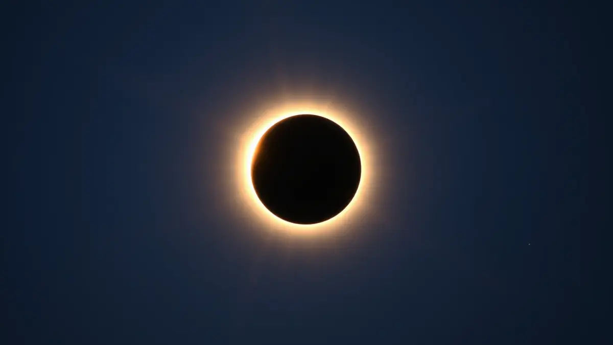 Imaxe xenérica dun eclipse solar parcial, coa lúa cubrindo parte do sol e un halo de luz.