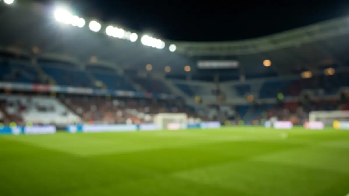 Imaxe xenérica dun estadio de fútbol baleiro pola noite, coas luces do campo e a herba verde.