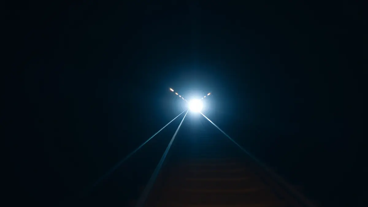 Imaxe xenérica dunha vía de tren nun túnel escuro con luces de emerxencia.