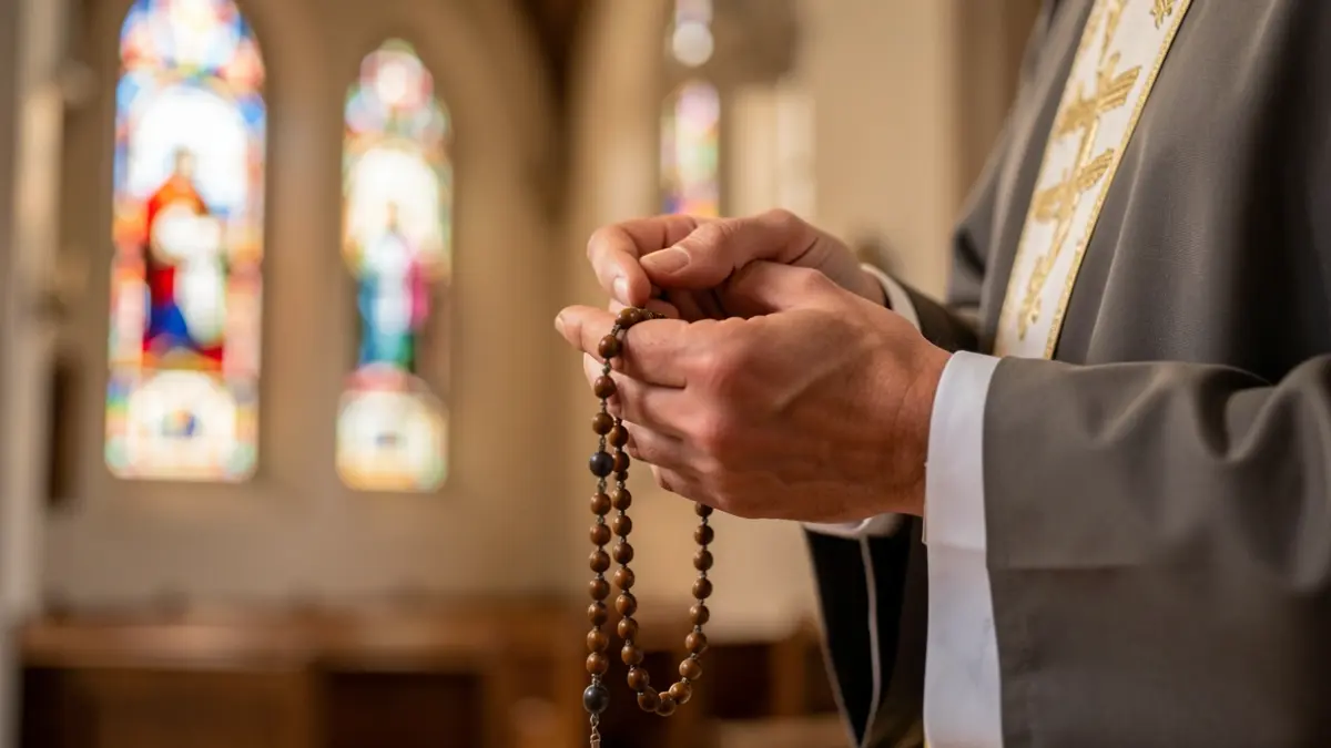 Primer plano de un sacerdote rezando con el rosario.