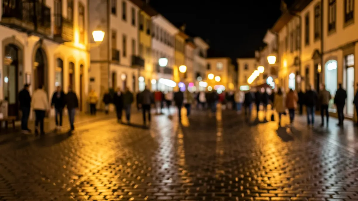 Imaxe xenérica dunha praza de vila galega pola noite, con luces cálidas e xente indistinta.