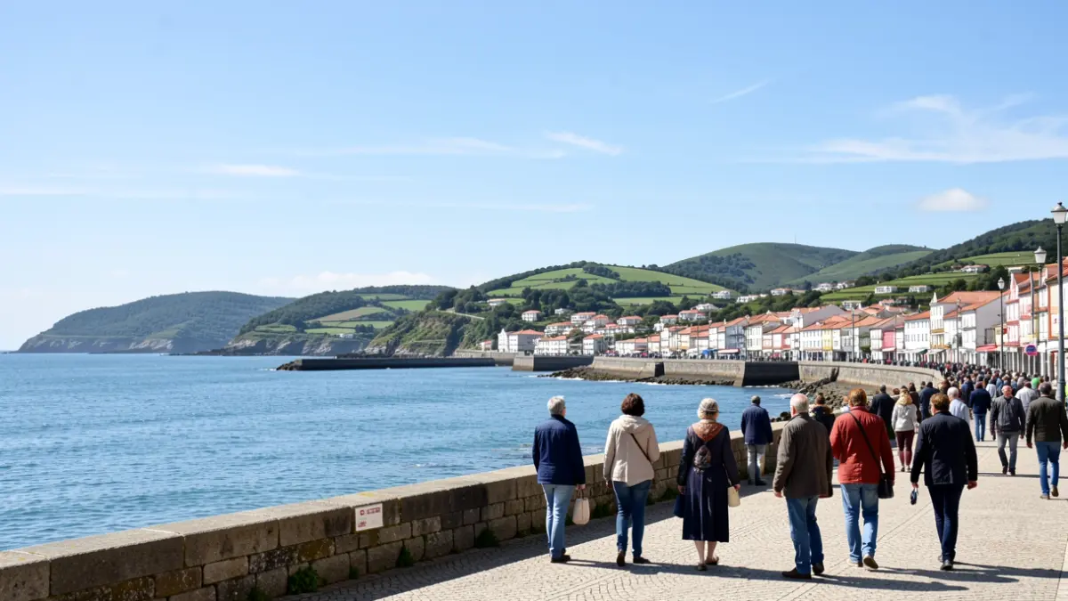 Cielo soleado sobre la villa costera de Carnota, Galicia, con mar en calma y colinas verdes al fondo.
