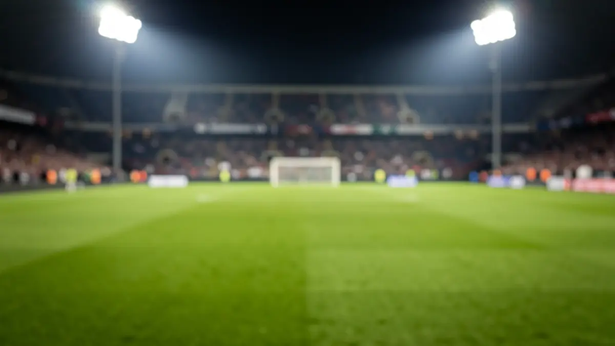 Imaxe xenérica dun estadio de fútbol pola noite, coas luces acendidas e o céspede.