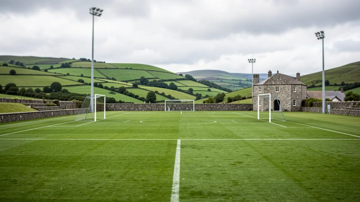 Imaxe xenérica dun campo de fútbol galego con arquitectura de granito e outeiros verdes.