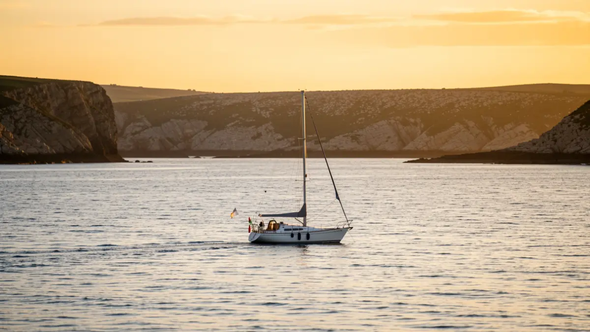 Un velero solitario en las aguas del Atlántico frente a la costa gallega al atardecer.