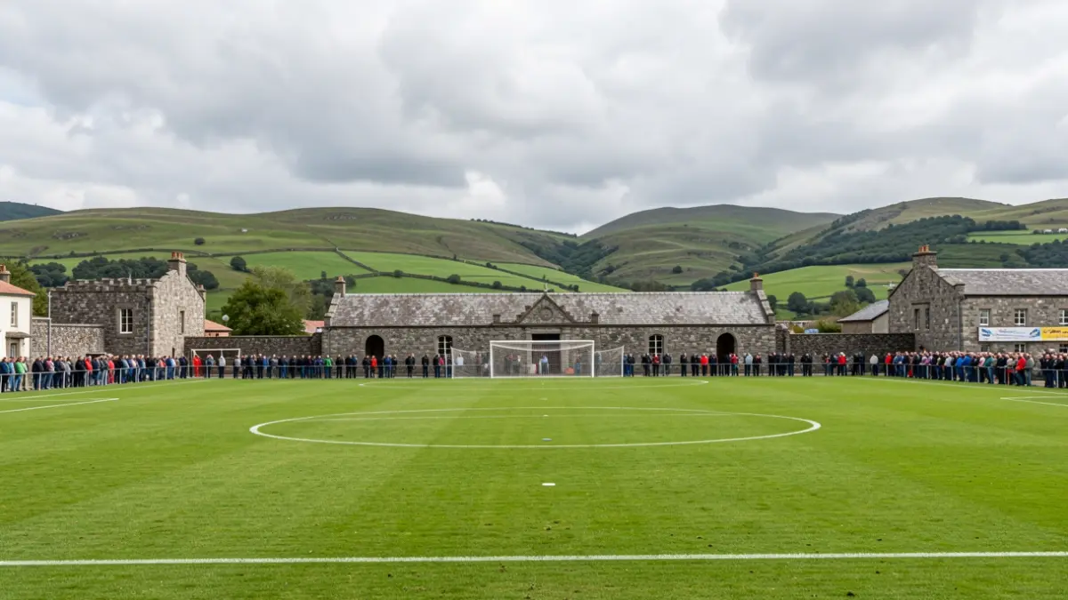 Imaxe xenérica dun campo de fútbol en Galicia con arquitectura de granito e outeiros verdes ao fondo, baixo un ceo nubrado.