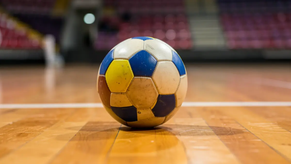 Imaxe xenérica dun balón de balonmán sobre unha pista deportiva.