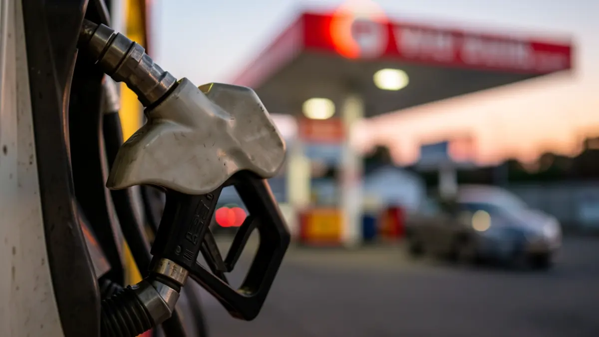 Primer plano de una pistola de gasolinera reflejando la luz del atardecer.
