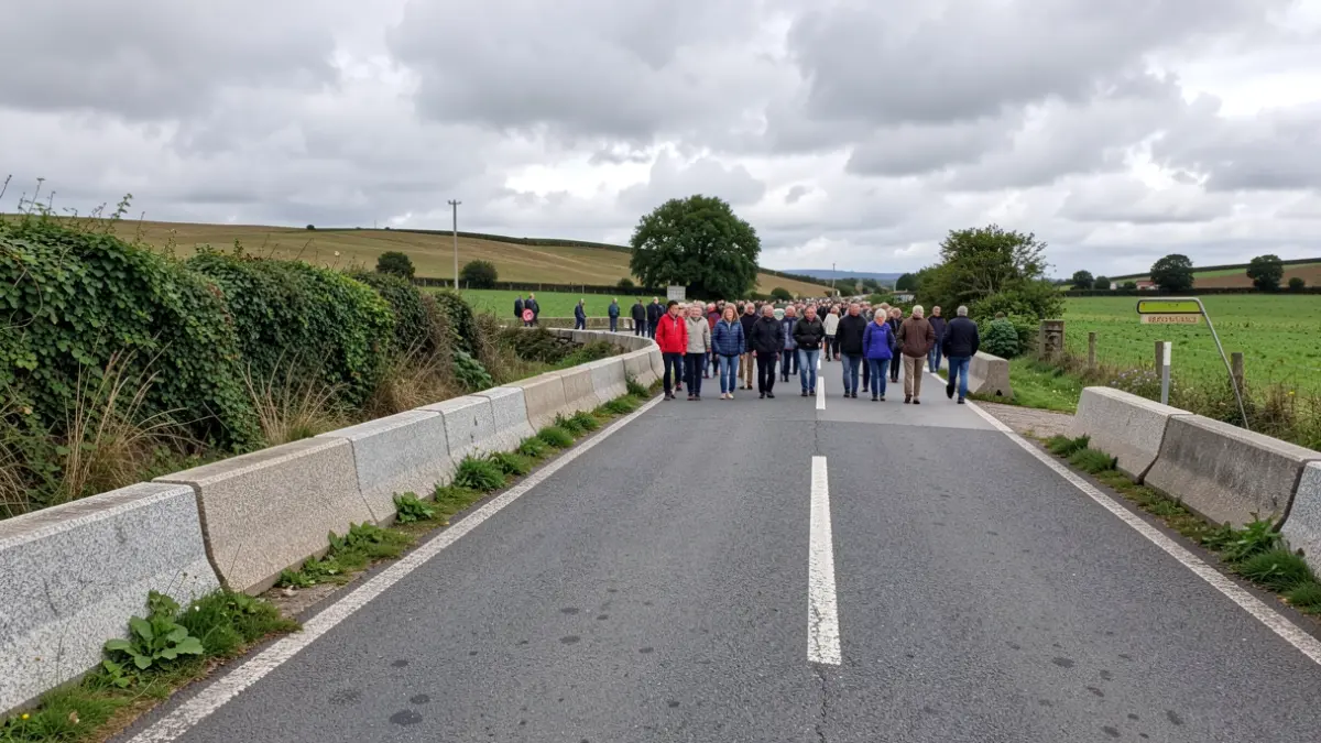 Imagen genérica de obras en una carretera rural gallega con barreras de granito y vegetación.