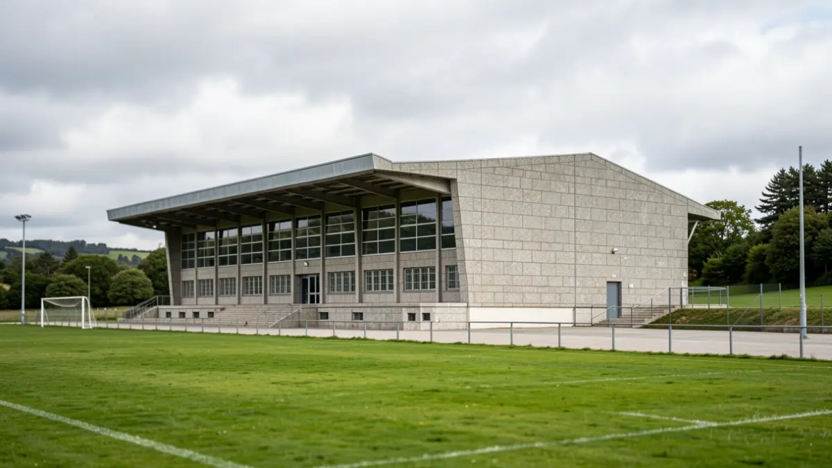 Imaxe xenérica dun pavillón deportivo de Galicia con fachada de granito e contorna verde.