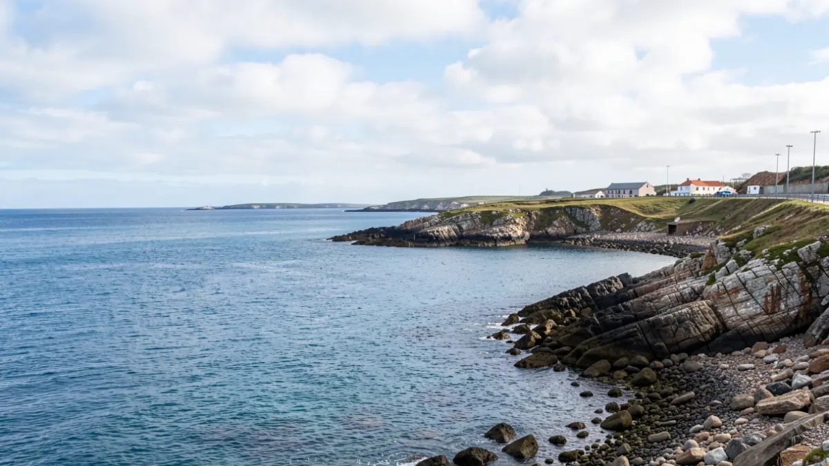 Imaxe xenérica da enseada de San Amaro na Coruña, con auga calma e costa rochosa.