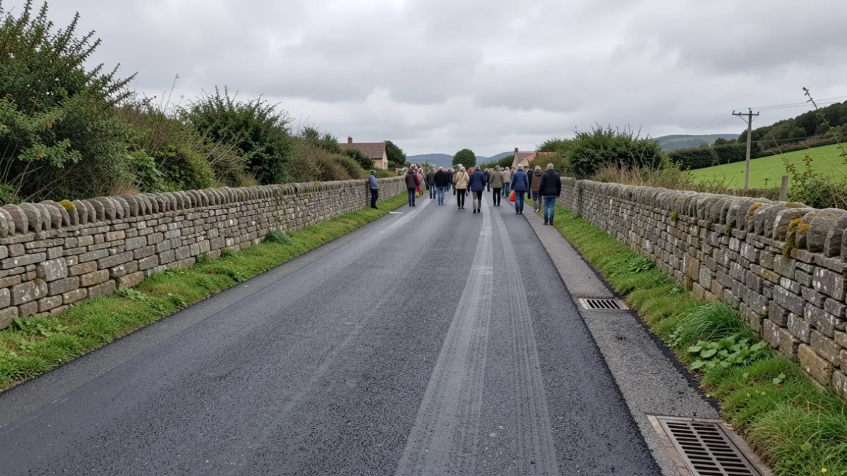 Imagen genérica de un camino rural gallego recientemente pavimentado con muros de piedra y vegetación.