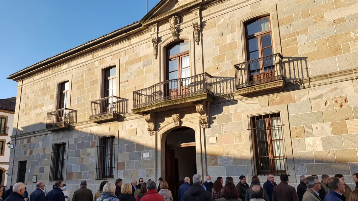 Imaxe xenérica dun concello galego con balcón e raís de ferro, luz de tarde.